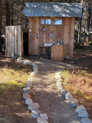 A rustic wooden cabin with a metal roof, a small table, and a bench.