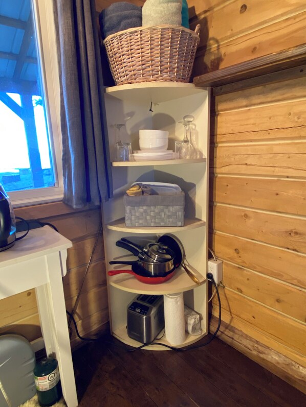 A corner shelf unit with kitchenware, a basket, and a white container.