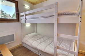 A bunk bed room with a window, a desk, and a wall-mounted heater. - 350m from resort center, 3rd floor, balcony, 32m², Méribel-Mottaret (Méribel - Les Allues)