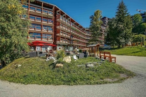 Ein mehrstöckiges Hotel mit Außenbestuhlung und einem angelegten Garten.