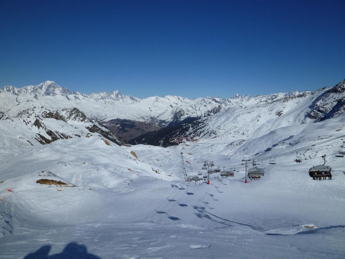 A snow-covered mountain landscape with ski lifts and a clear blue sky.