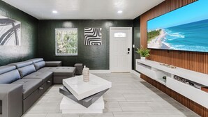 Una sala de estar moderna con un sofá modular, una mesa de centro, un televisor de pantalla plana y vista al océano.