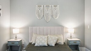 Une chambre à coucher avec un lit, deux tables de chevet avec des lampes et une décoration murale au-dessus du lit.