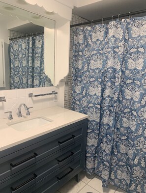 A bathroom with a white sink, a mirror, and a blue floral shower curtain.