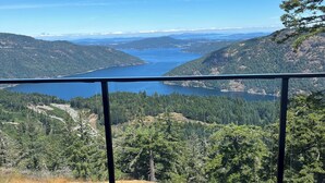 Un balcón con vistas a un lago rodeado de colinas boscosas.