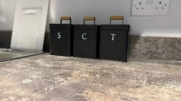 Three black storage bins labeled 'S', 'C', and 'T' on a kitchen countertop.