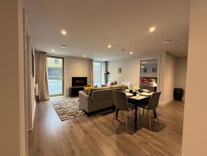 Een moderne woonkamer met een bank, eettafel en televisie.