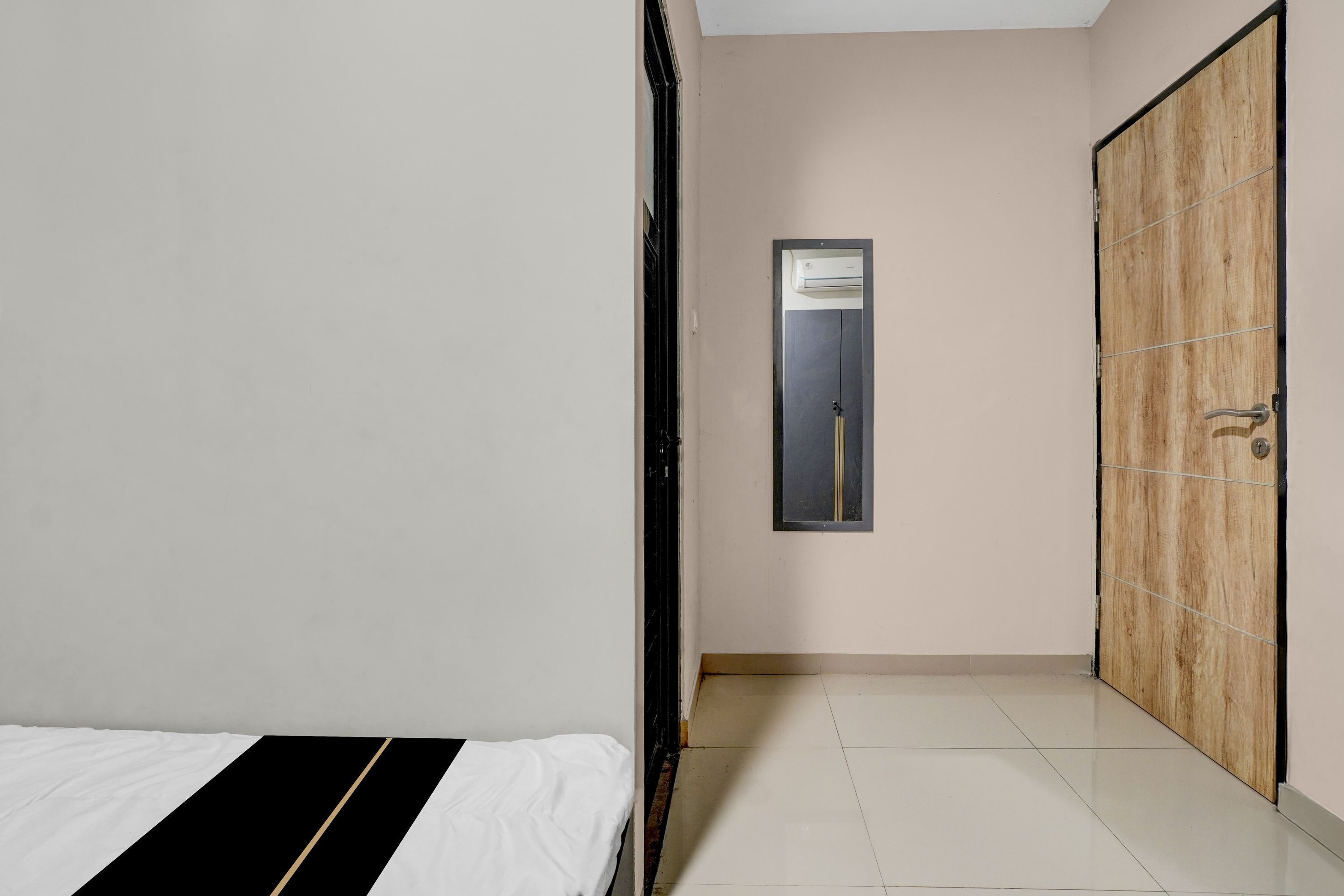 A bedroom with a bed, a wardrobe, and an air conditioning unit.