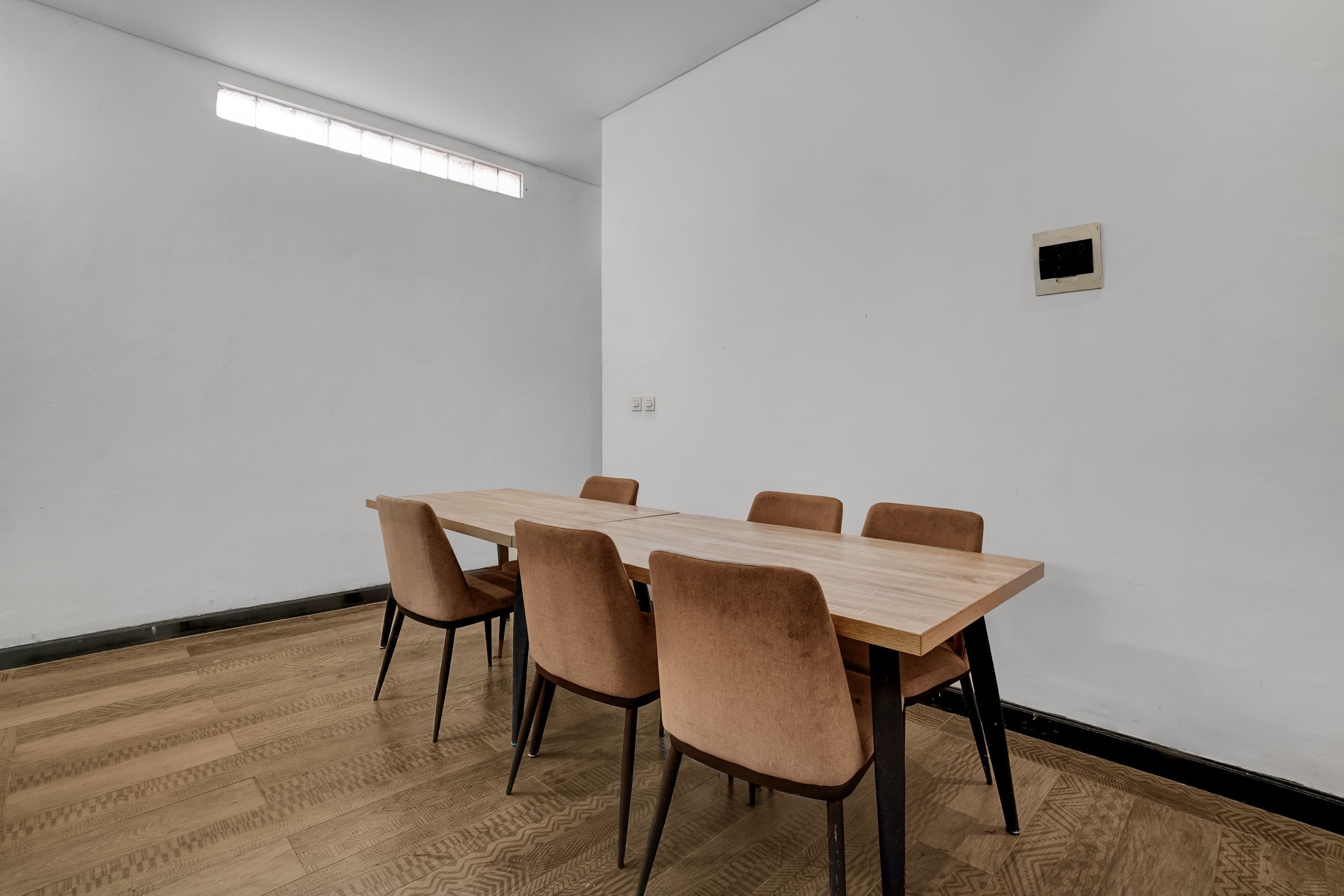 Una sala de conferencias con una mesa rectangular, seis sillas y un ventanal.