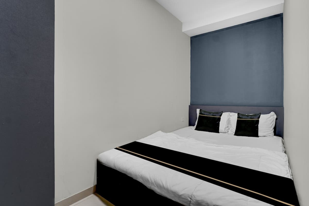 A bedroom with a bed, a headboard, and a wall.
