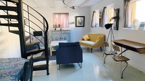 A modern living room with a spiral staircase, a sofa, a desk, and a chair.