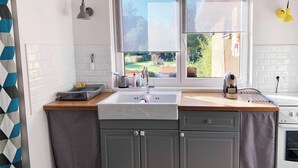 A kitchen with a window, a sink, a kettle, and a toaster.