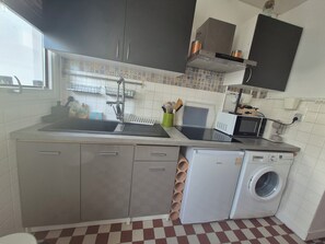 A compact kitchen with a sink, a microwave, a washing machine, and a window. - townhouse (Le Verdon-sur-Mer)