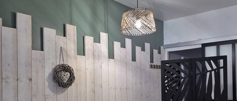 A room with a bed, a hanging light fixture, a decorative wall panel, and a partial view of a wardrobe.