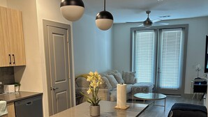 Una cocina moderna con una isla central, armarios de madera y un cubo de basura negro.