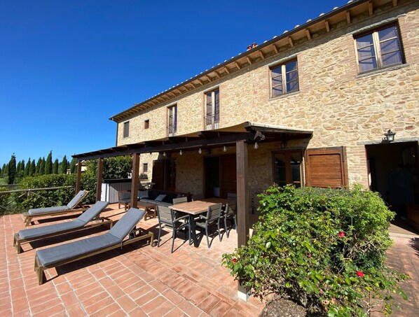 A stone building with a patio area featuring sun loungers and a table.
