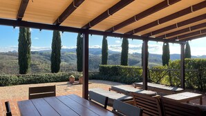 Un espacio de estar al aire libre cubierto con vistas a colinas ondulantes y árboles.