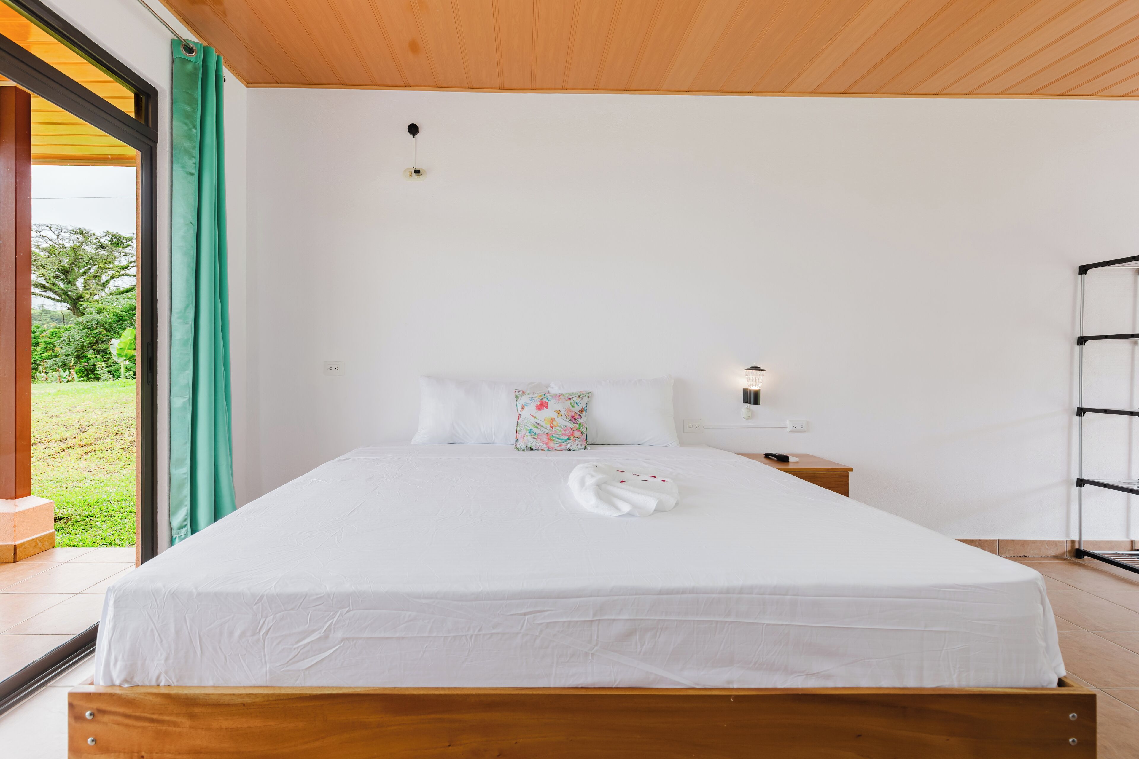 Un letto rifatto con un piumone bianco, un cuscino floreale e un asciugamano bianco su un lato.