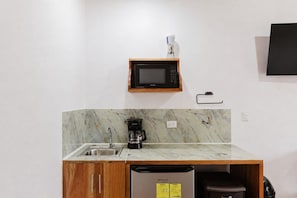 A compact kitchenette with a built-in microwave, a coffee maker, a sink, and a dishwasher. - Blue Mountain Lodging Arenal (Monterrey)