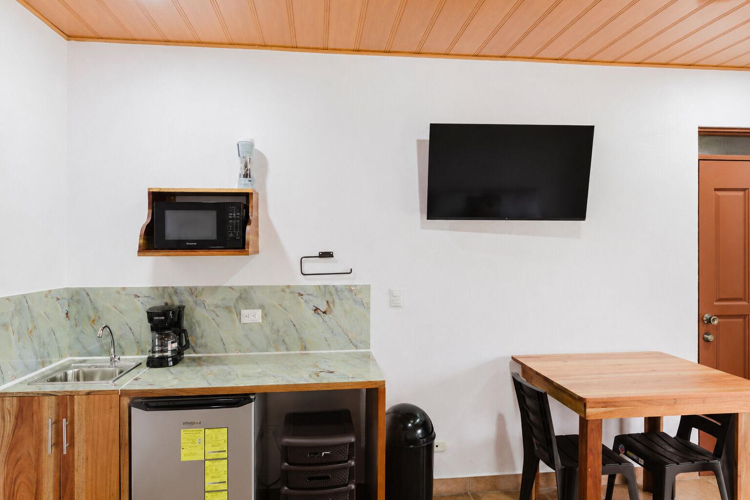 A compact kitchen with a microwave, coffee maker, and refrigerator.