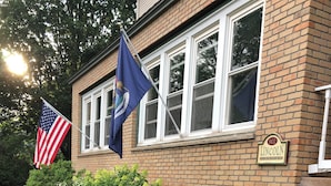 Een bakstenen gebouw met een stenen muur en een wimpelstok met een Amerikaanse vlag en een blauwe vlag.