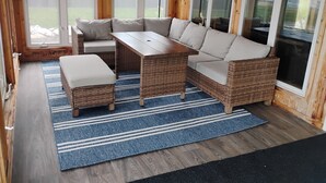 Una habitación acogedora con un sofá seccional, una mesa de madera y una alfombra azul a rayas.