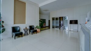 Un vestíbulo moderno con mostrador de recepción, zona de estar y un gran muro decorativo.