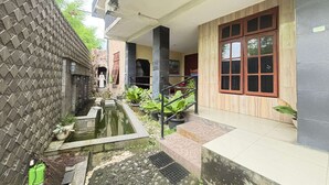 A courtyard with a small water feature, steps leading to a covered area, and a brick wall. - OYO 95097 Griya Asri Guest House (Depok)