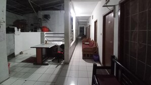 A corridor with a tiled floor, a table with chairs, a sofa, and a door on the right. - OYO 95096 Dewi Sudirman Guest House (Bandung)