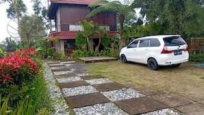 Un coche blanco estacionado en un jardín con un camino de piedra que lleva a un edificio.