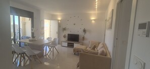Una sala de estar moderna con comedor, un sofá, un televisor y una planta montada en la pared.