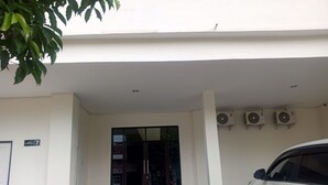 A building entrance with a glass door, air conditioning units, and a parked car. - OYO 95103 Madiun Dkost Syariah (Madiun)