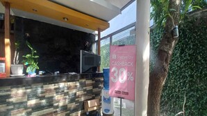 A reception area with a stone wall, a water dispenser, and a sign offering a 30% cashback on Shopee Pay. - OYO 95106 A Homestay Syariah (Sambi)