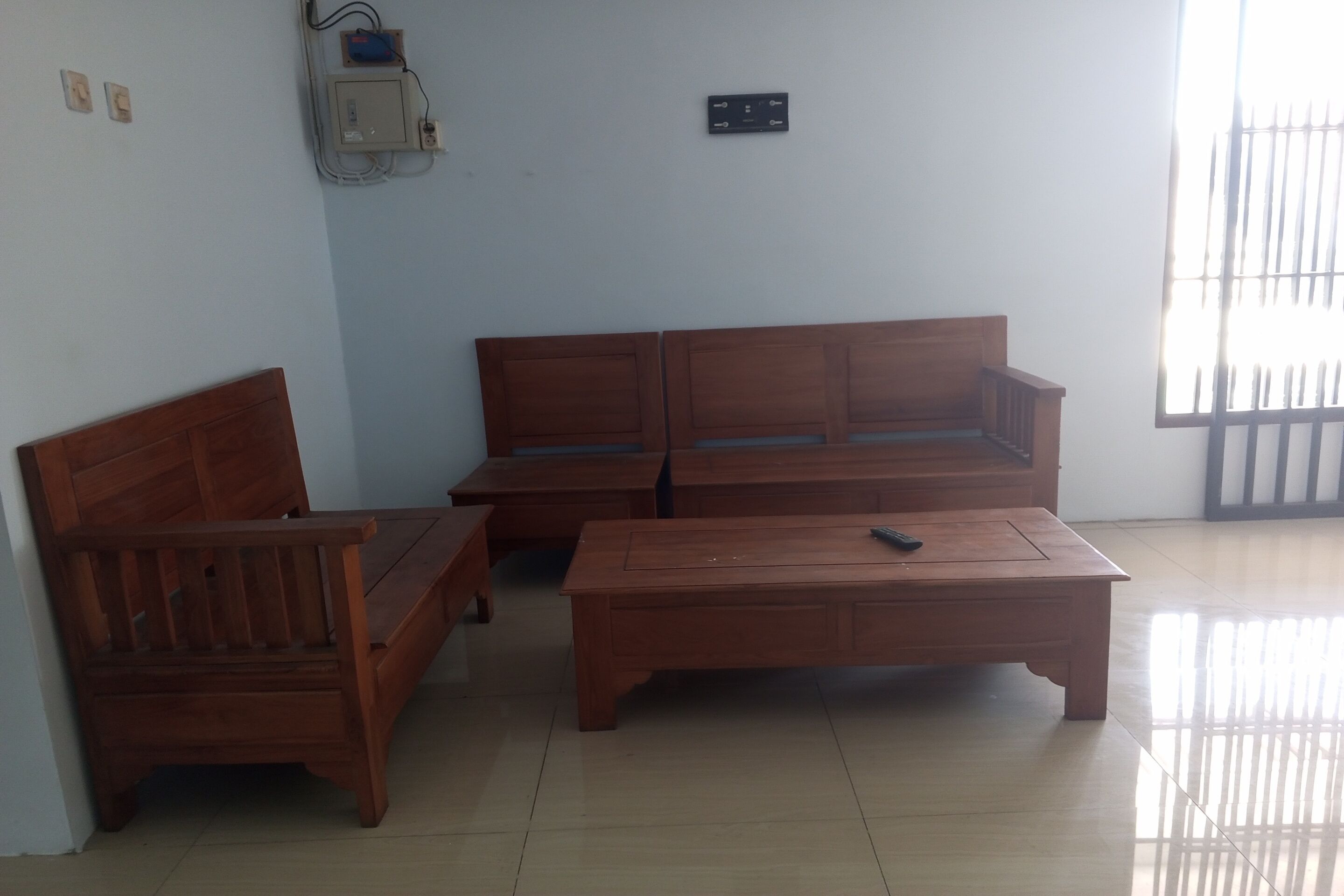 A room with a wooden sofa, a wooden bench, and a wooden coffee table.