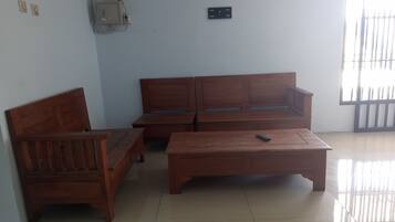 A room with a wooden sofa, a wooden bench, and a wooden coffee table.