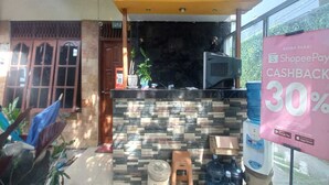 A reception area with a stone wall, a counter, and a sign offering a 30% cashback on Shopee Pay. - OYO 95106 A Homestay Syariah (Sambi)