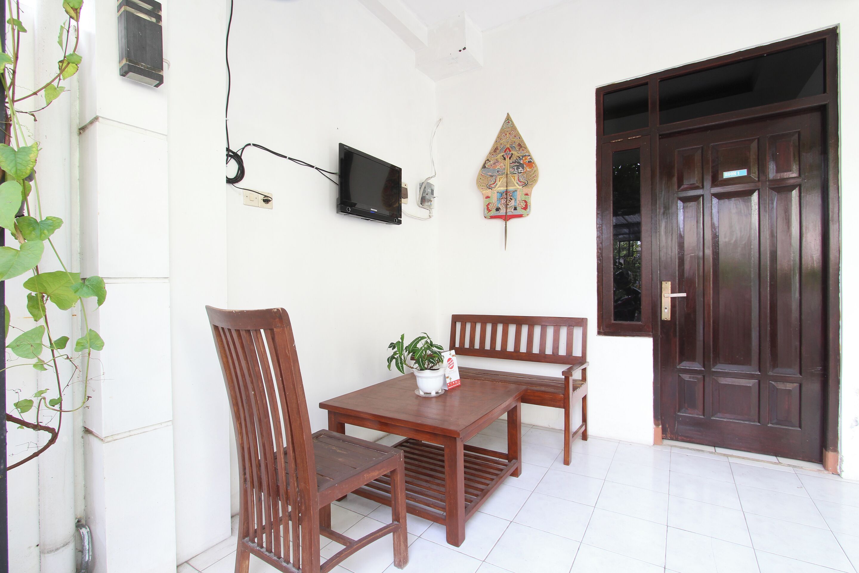 A room with a wooden table and chairs, a television mounted on the wall, and a decorative item above the door.