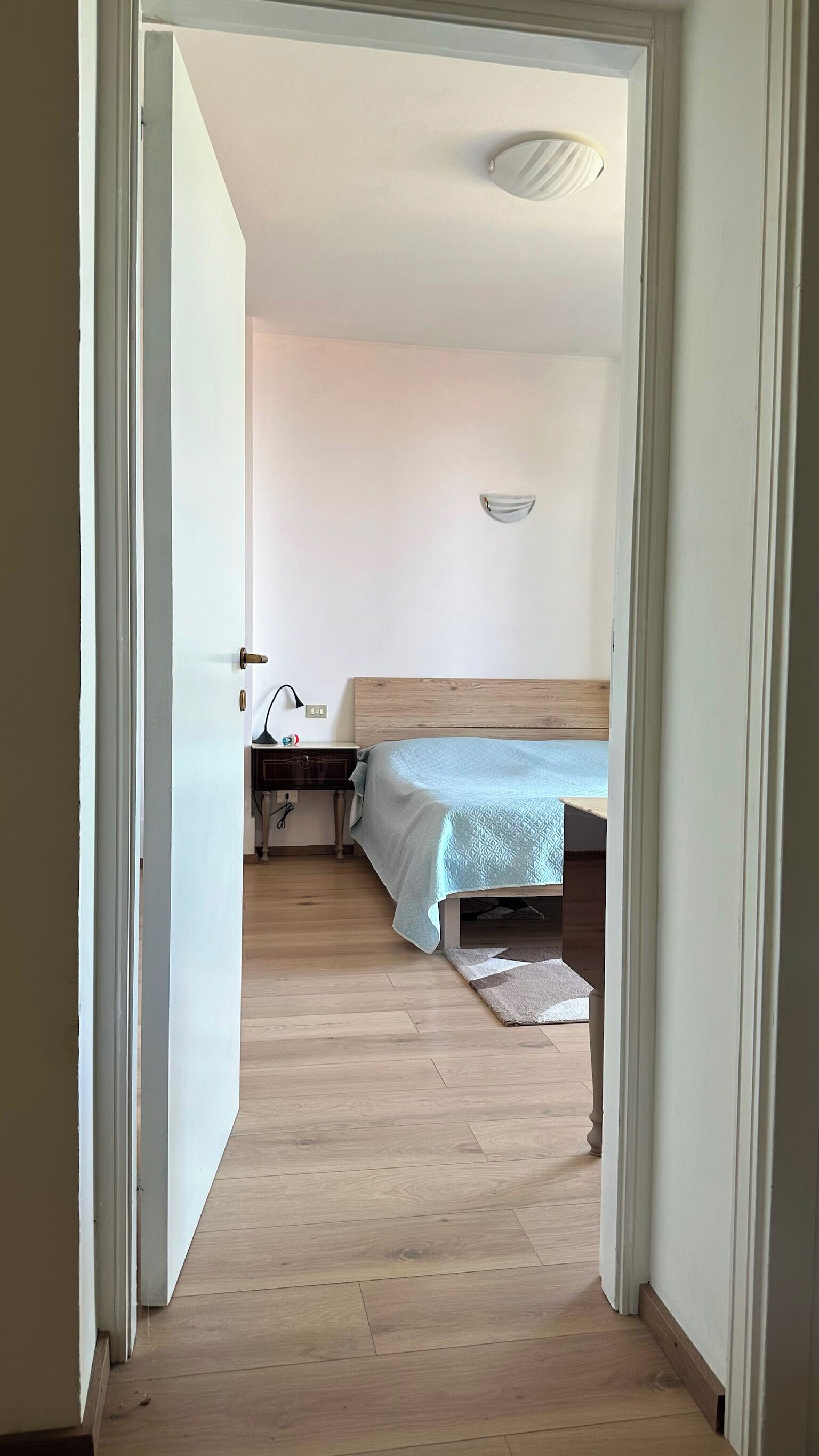 Ein Schlafzimmer mit einem hölzernen Bett, einem Nachttisch, einer Lampe und einer Wandleuchte.