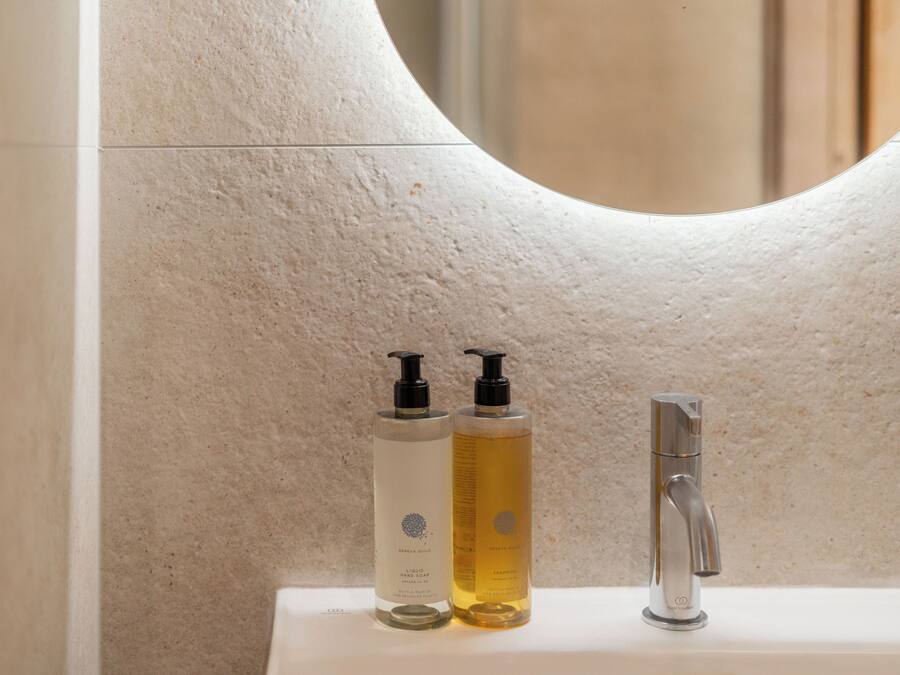 A bathroom with a white sink, two bottles of liquid soap, and a modern faucet.