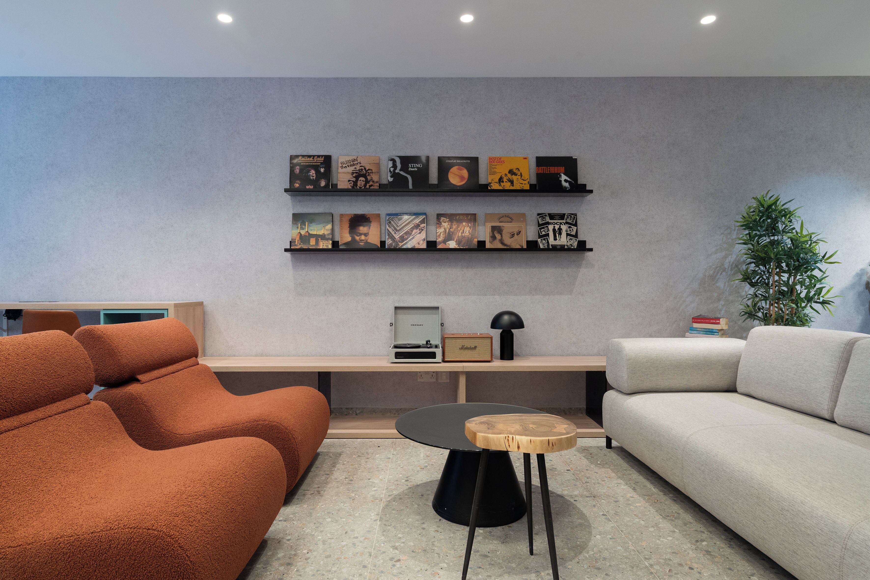 Una sala de estar moderna con un sofá, una mesa de centro y una estantería con objetos enmarcados.