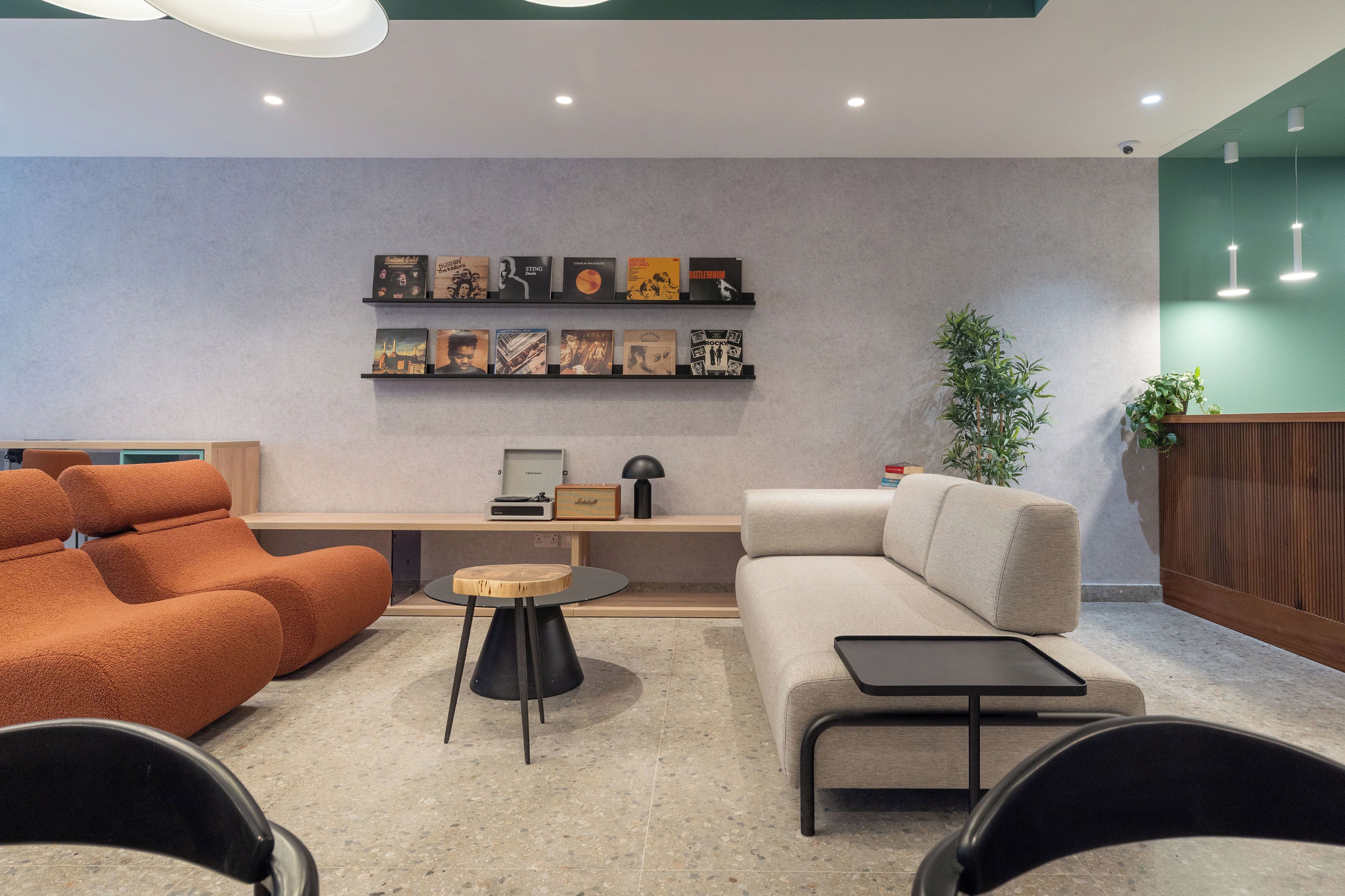 Un hall d’entrée moderne avec un canapé, des fauteuils, une table basse et un mur orné de tableaux.