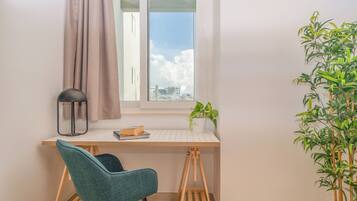 Un espacio de trabajo con escritorio, silla, ventana, cortina y una planta en maceta.