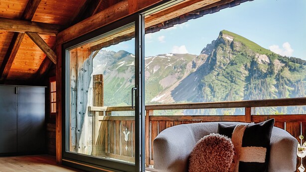 Un interno in legno con un'ampia finestra vista montagna.