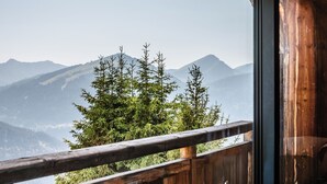 Un balcone in legno con vista su montagne e alberi.