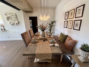 A dining area with a wooden table, cushioned chairs, a woven runner, and a hanging light fixture. - 2-bedroom apartment in charming West Hollywood with AC and gym access (West Hollywood)