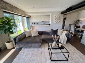 A modern living room with a sectional sofa, a coffee table, and a dining area with chairs and a table. - 2-bedroom apartment in charming West Hollywood with AC and gym access (West Hollywood)