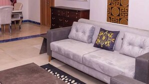 Un soggiorno con un divano grigio, una parete decorata, un quadro e un mobile in legno.