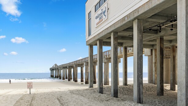 A pier with a sign reading "The Whistling Duck" extending over a sandy beach. - Private Heated Pool, Hot Tub, 1-min Walk to Beach, Pet Friendly, King Bed (Surfside Beach)