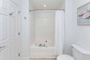 A bathroom with a bathtub, toilet, and shower curtain. - Private Heated Pool, Hot Tub, 1-min Walk to Beach, Pet Friendly, King Bed (Surfside Beach)