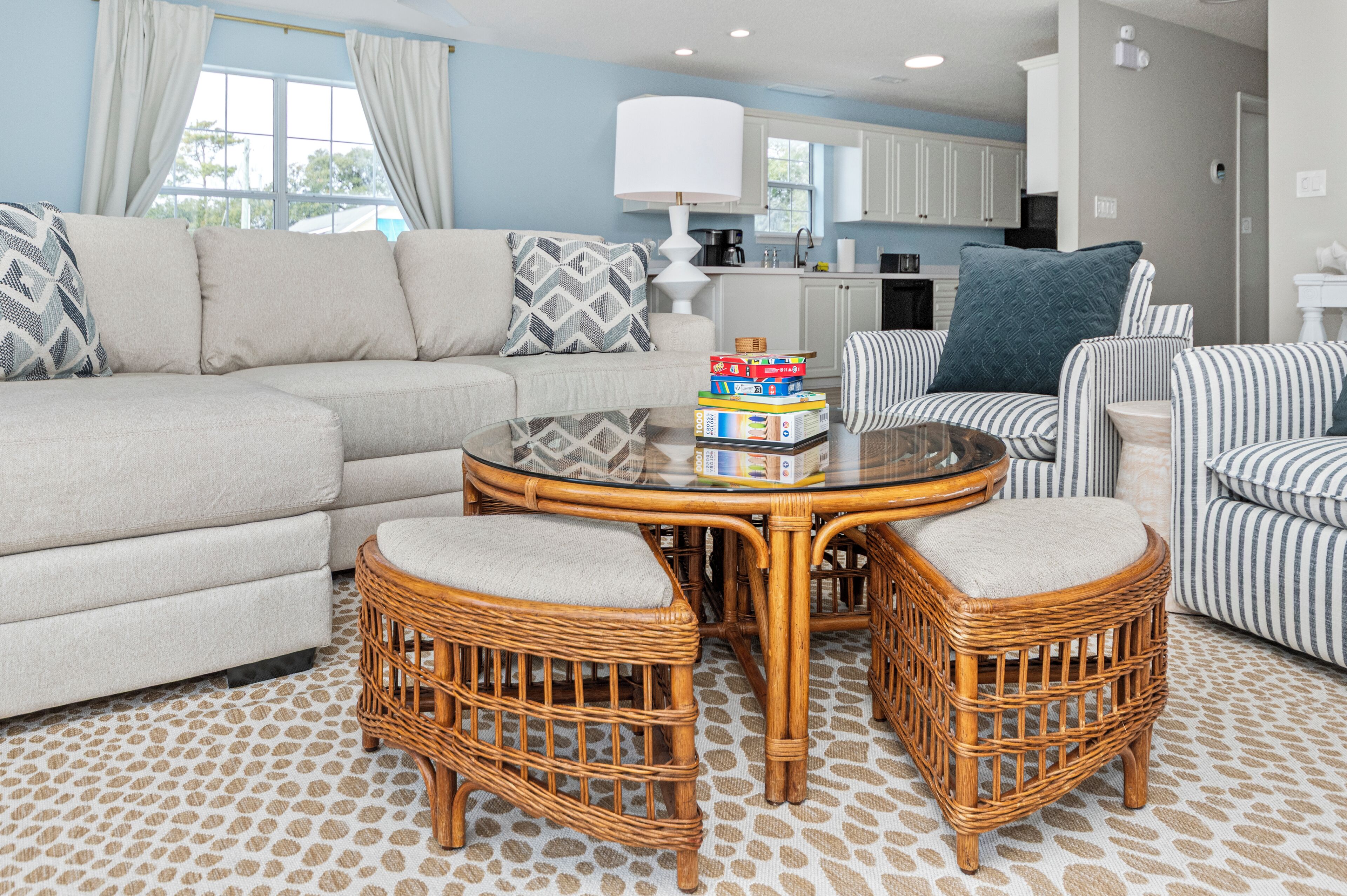 A living room with a sofa, two wicker chairs, a coffee table, and a striped armchair.